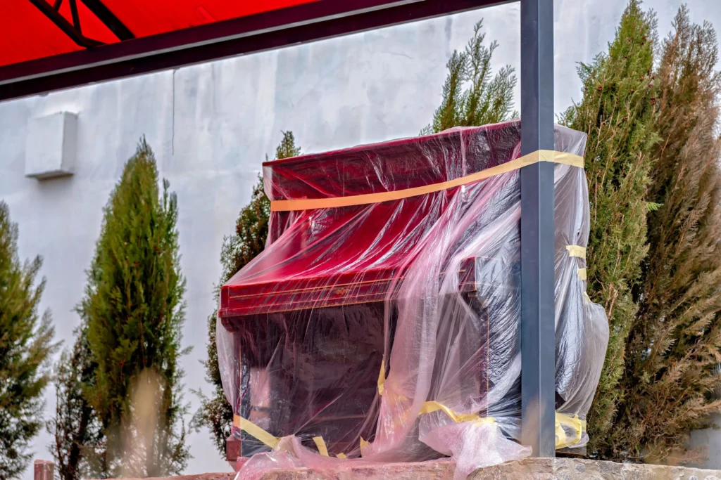 Current image: professional movers relocating a piano using specialized moving equipment